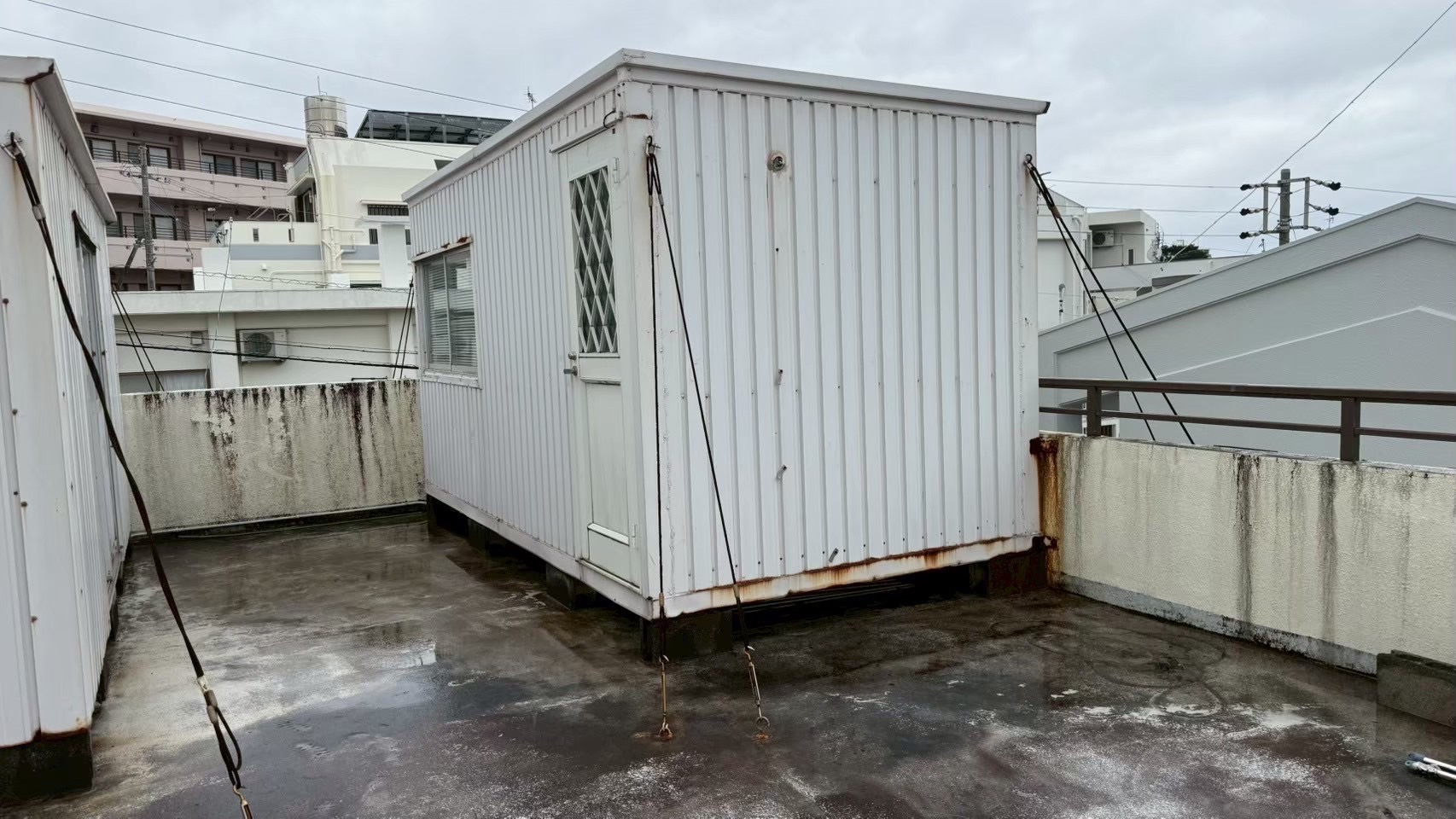 うるま市の屋上にワイヤーで固定されたコンテナ型プレハブ